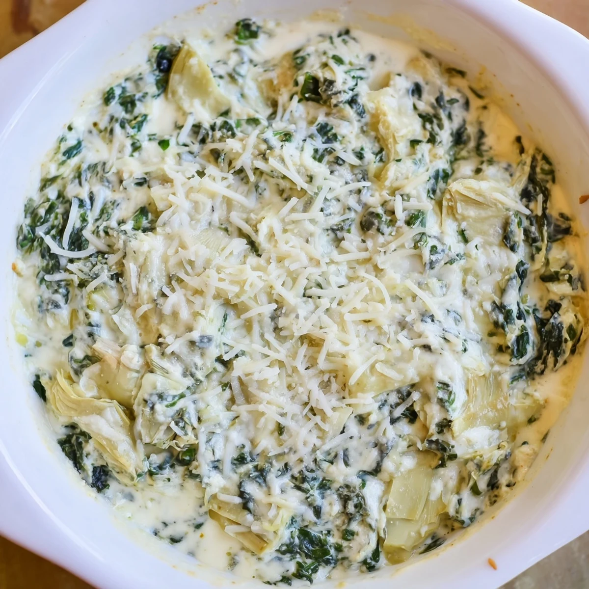 A warm bowl of Creamy Spinach and Artichoke Dip bubbling with melted mozzarella and Parmesan, served with tortilla chips for dipping.