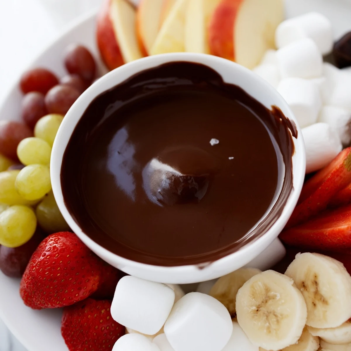 Steamy chocolate fondue pot with marshmallows and sliced fruit for sharing.