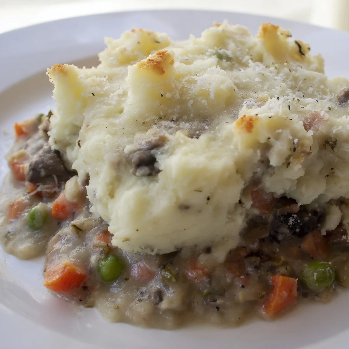 Rich Shepherd's Pie filling with tender lamb chunks, carrots, and peas under fluffy mashed potatoes.