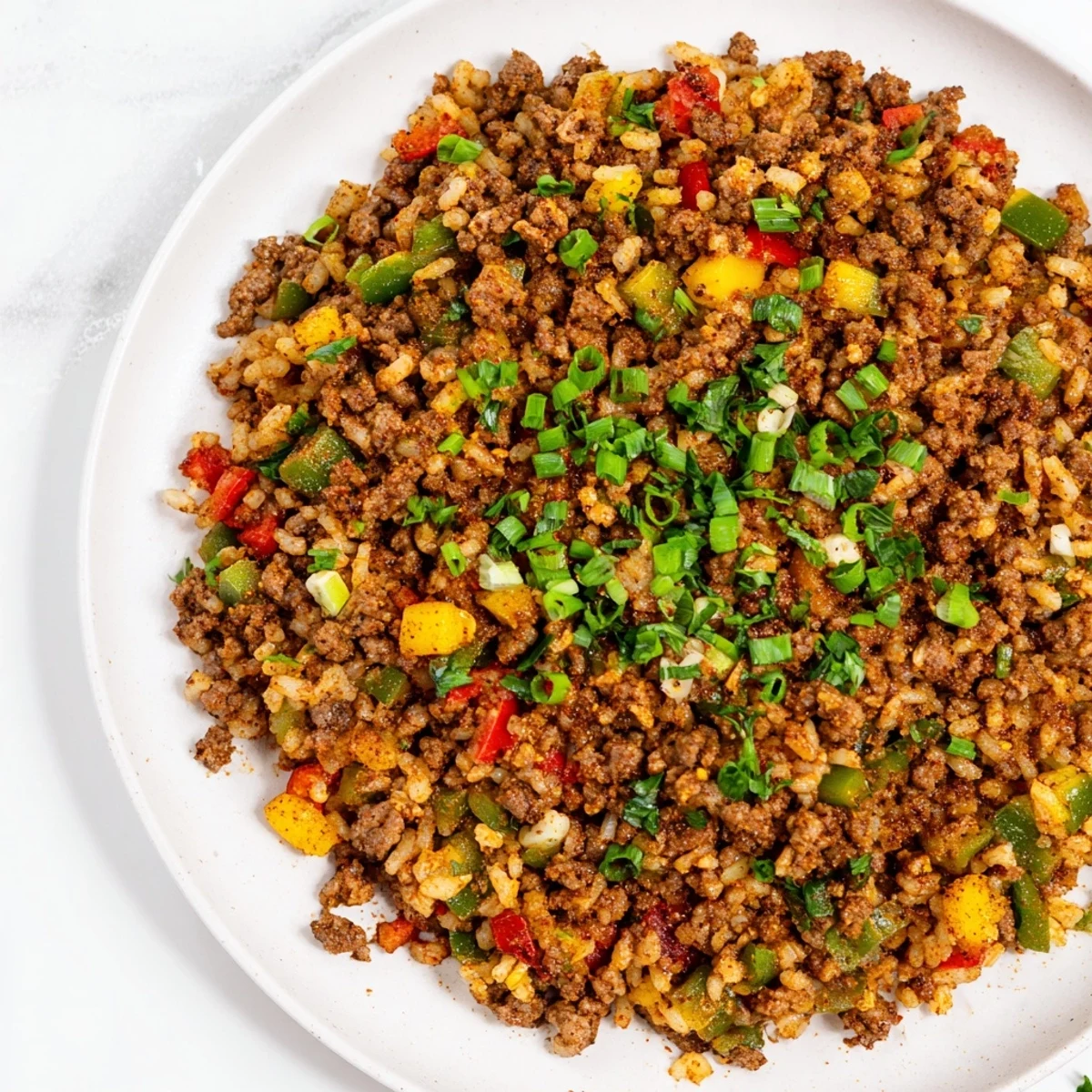 A serving bowl of Cajun Dirty Rice with Ground Beef and Peppers, topped with fresh parsley and vibrant diced peppers.