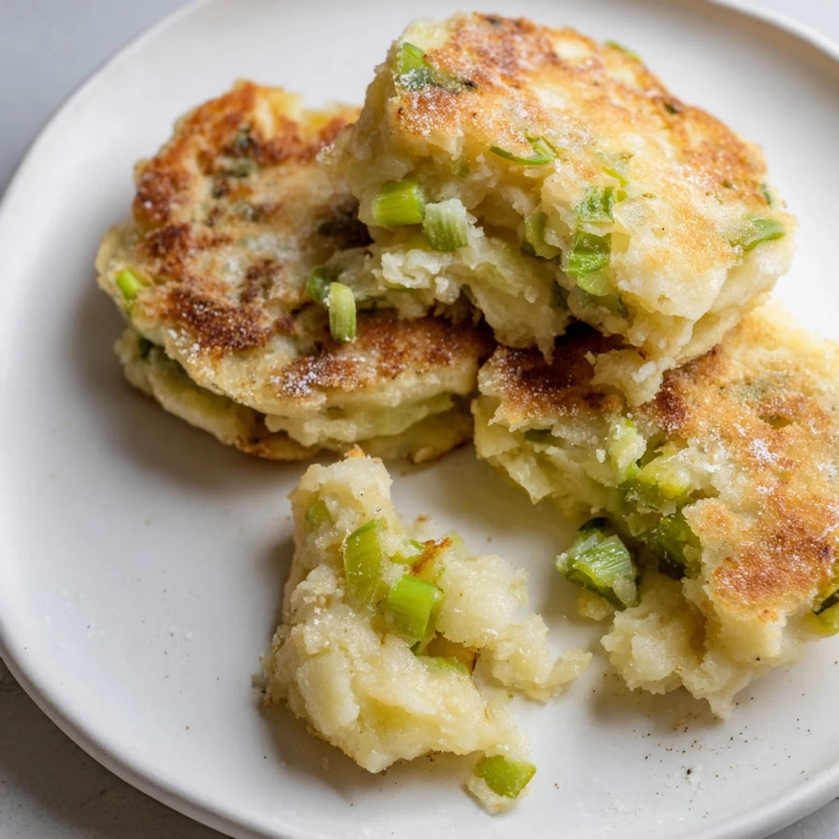 Golden-brown Irish Potato Cakes with Scallions sizzling in a skillet, ready for breakfast.  
