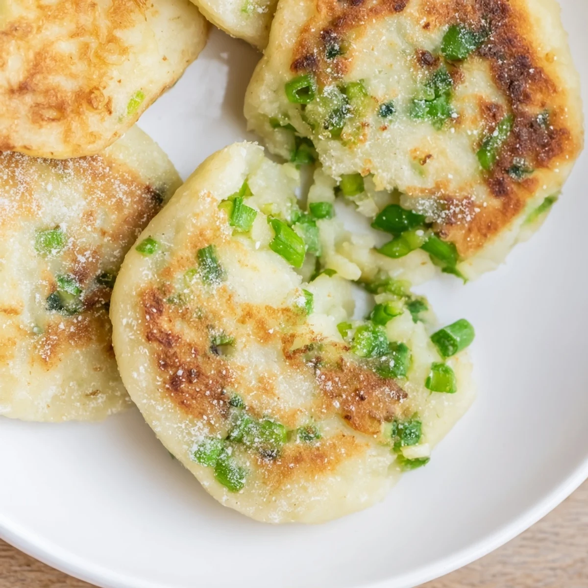Rustic, pan-fried Irish Potato Cakes with Scallions on a white plate for a side dish.