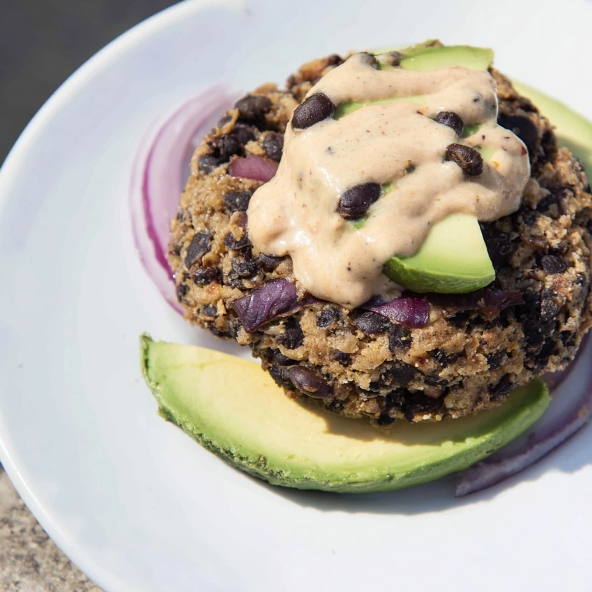 The Vegan Black Bean Burger with Chipotle Mayo is stacked high with tomato and onion on a soft bun, ready to serve.