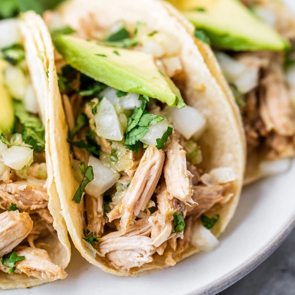 Close-up of juicy Chicken Street Tacos garnished with cotija cheese and lime wedges, served on a rustic wooden table for an authentic Mexican dinner.