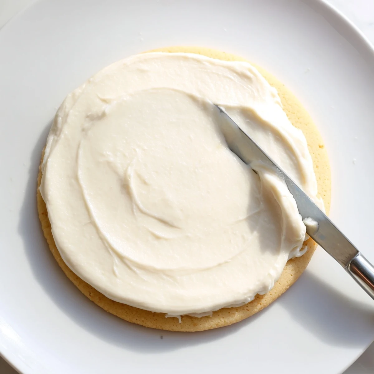 The creamy Easy Sugar Cookie Frosting is being piped onto a decorated cookie, creating beautiful swirls and patterns.