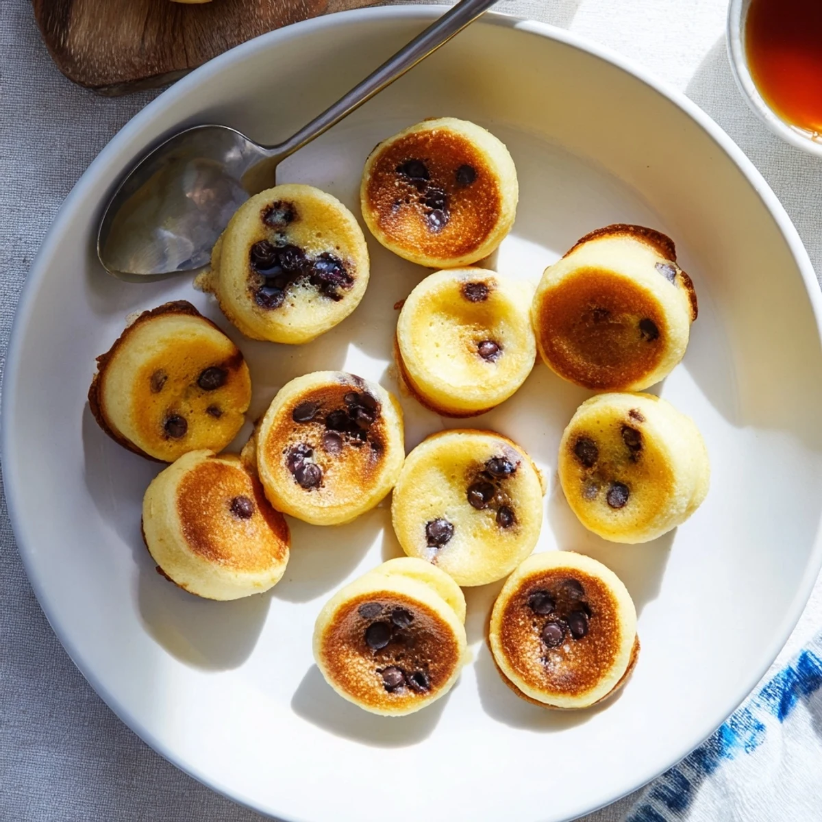 Golden-brown Pancake Poppers lined up in a muffin tin, perfect for dipping in maple syrup.