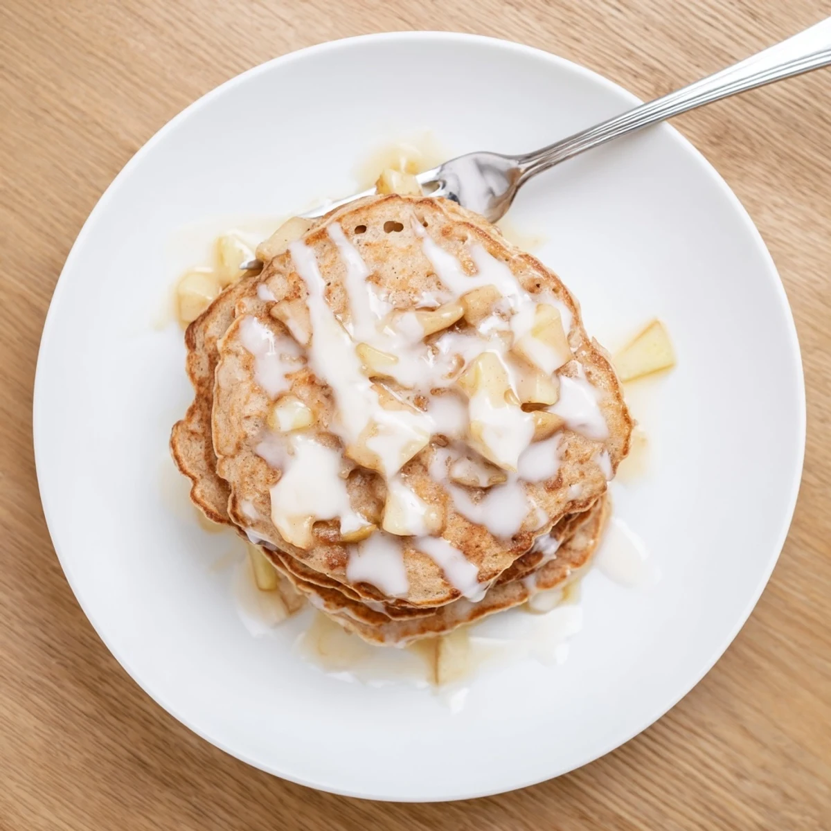Warm Apple Fritter Pancakes on a white ceramic plate, featuring a sweet vanilla glaze and soft, fluffy texture.