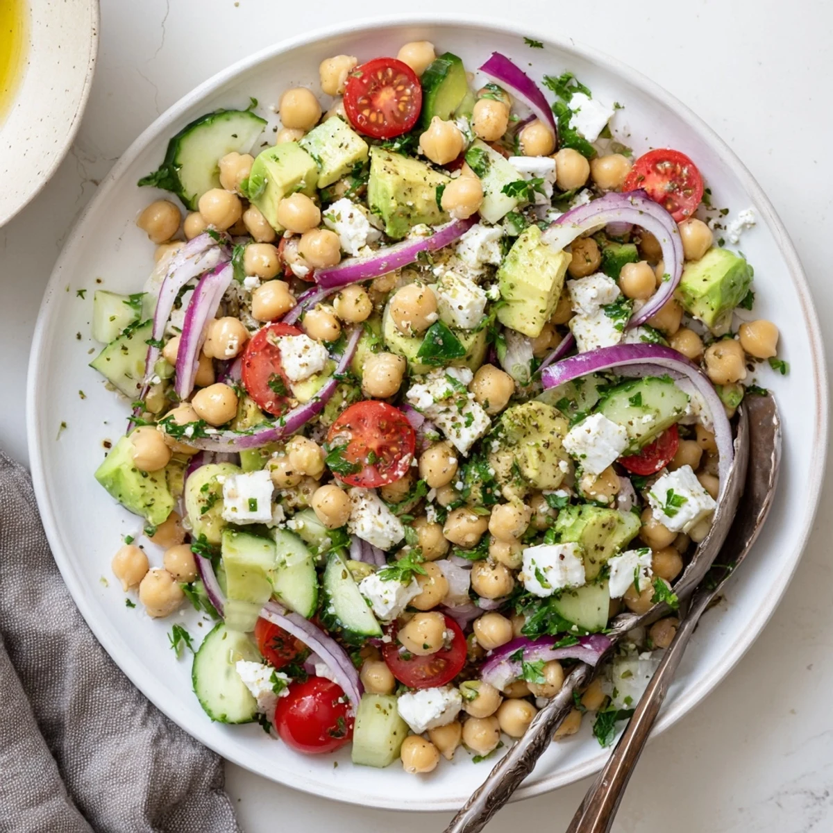 Fresh chickpeas, diced avocado, and cherry tomatoes in a Chickpea Feta Avocado Salad served over crisp greens.