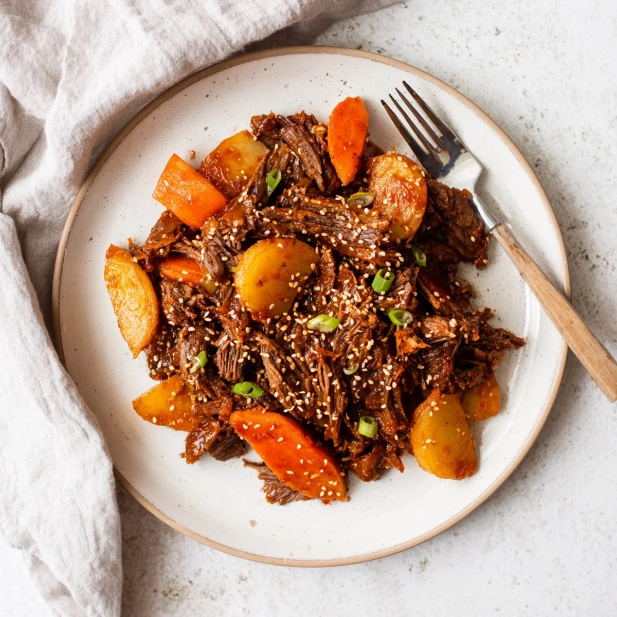 Savory Korean Style Pot Roast simmered in a rich, glossy sauce with chunks of beef, carrots, and daikon in a Dutch oven.