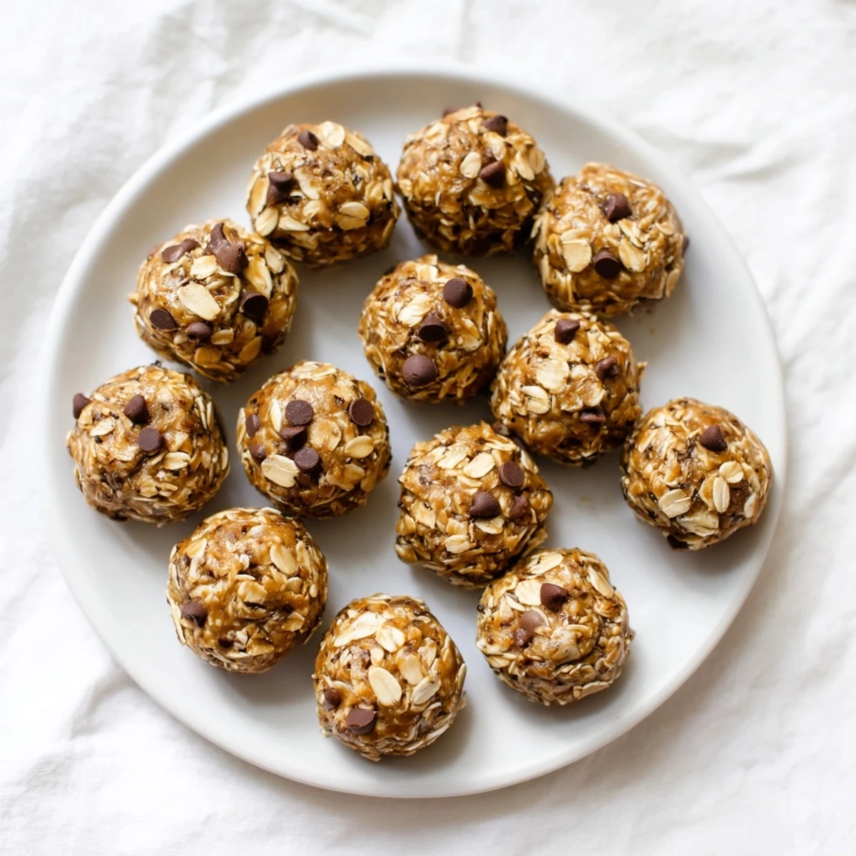 No Bake Peanut Butter Energy Bites stacked on a plate with a glass of milk for an afternoon snack.