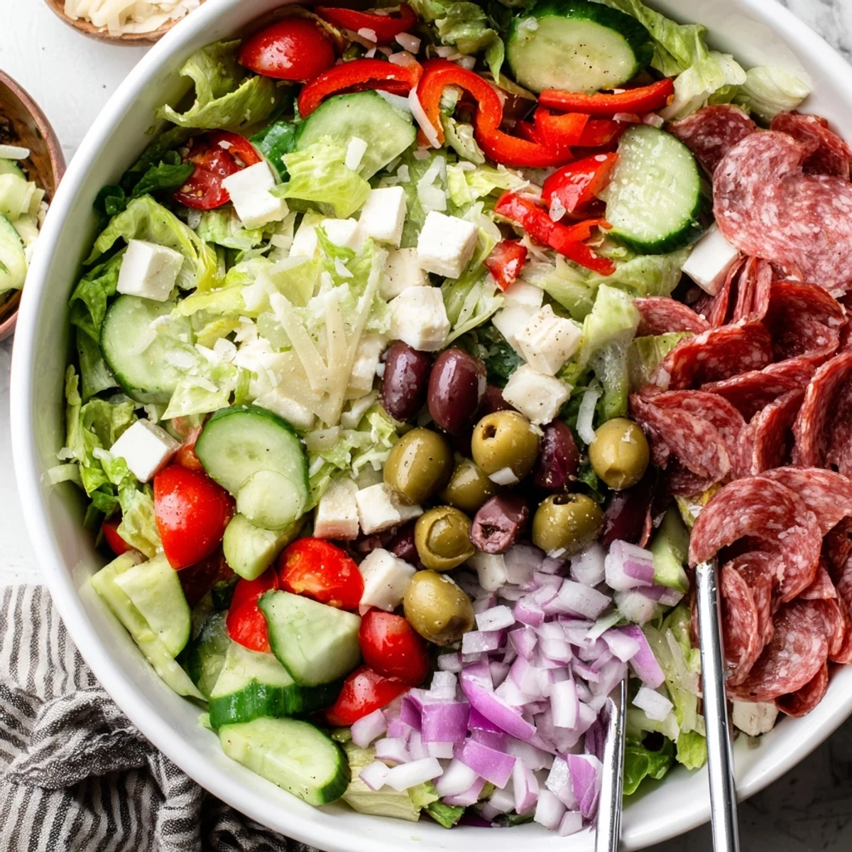 Serving bowl of fresh Italian chopped salad featuring diced vegetables, cheese, pepperoncini, and savory homemade Italian dressing