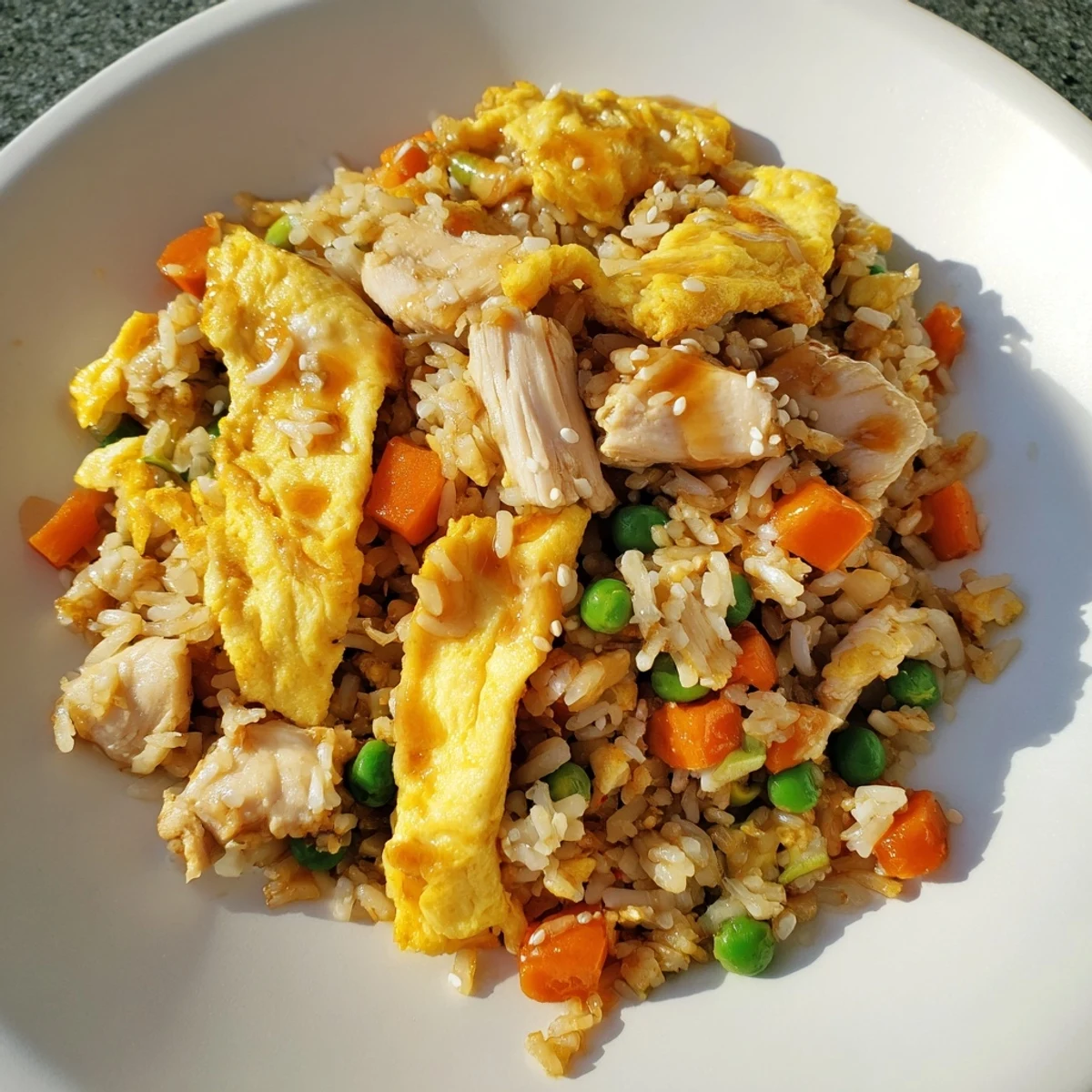 Asian-style chicken fried rice dish with sliced omelette topping served family style with scallion garnish