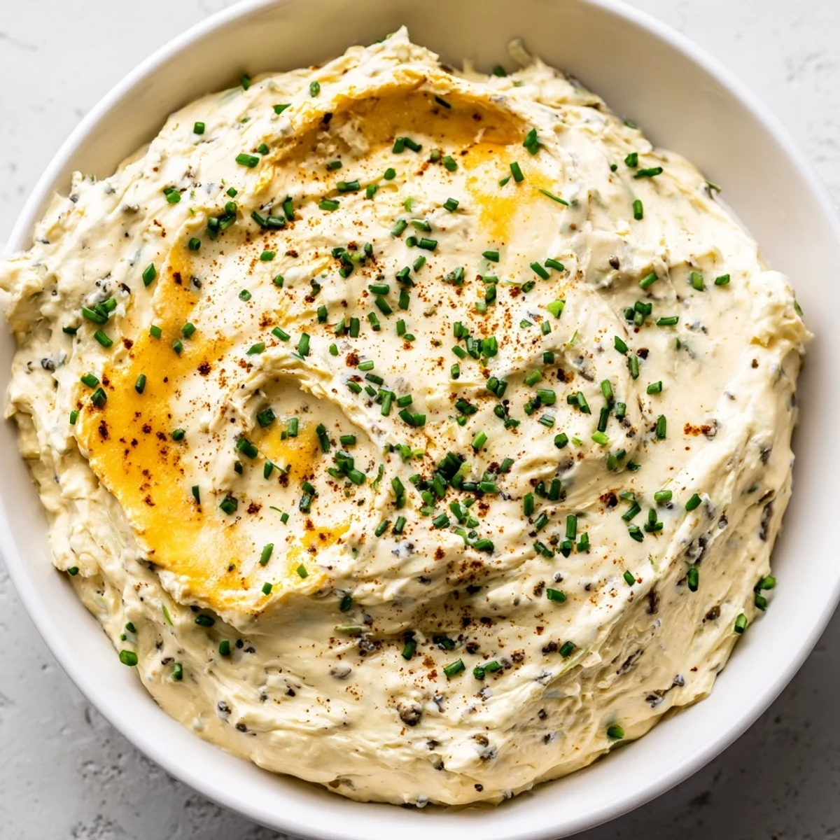 Creamy savory pretzel dip with melted cheddar and fresh chives served in a white bowl