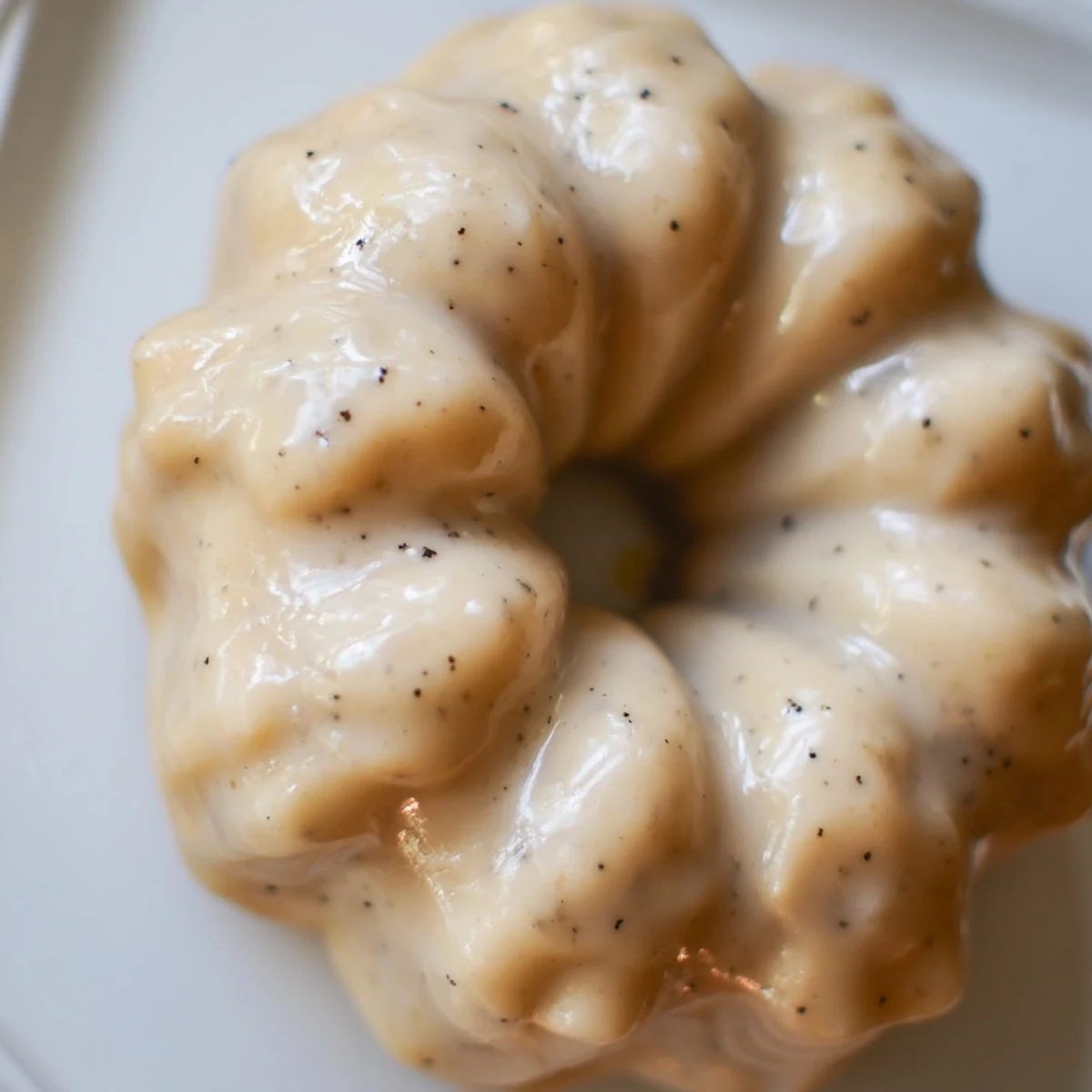 Golden brown Earl Grey mochi donuts drizzled with white tea glaze on a wire rack