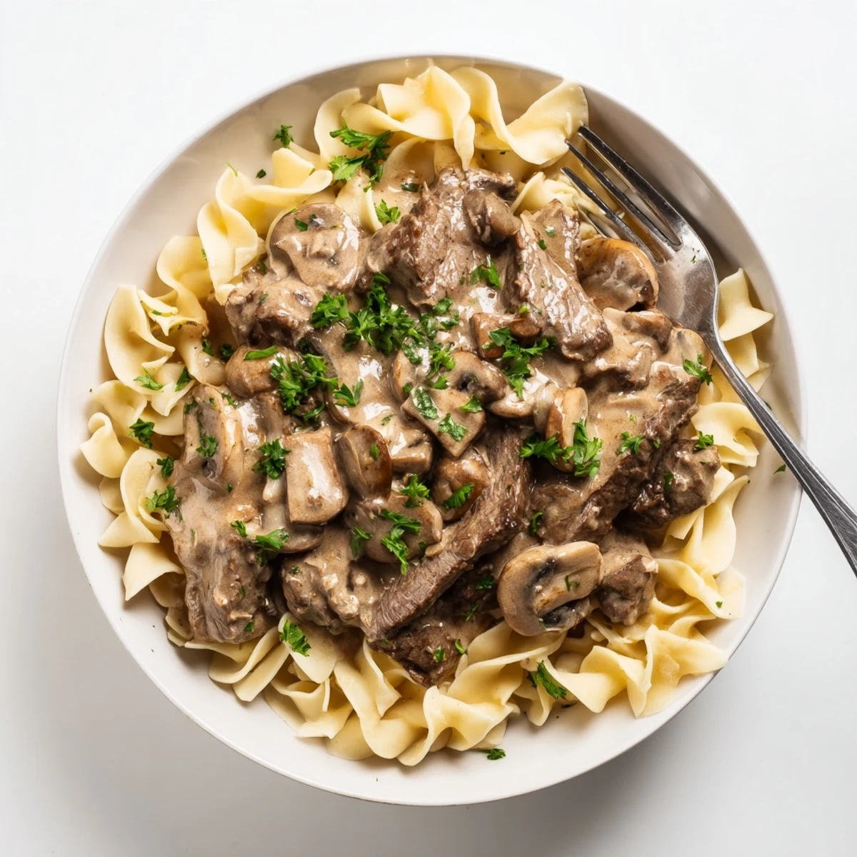 Homemade beef stroganoff with golden mushrooms and creamy sauce atop egg noodles