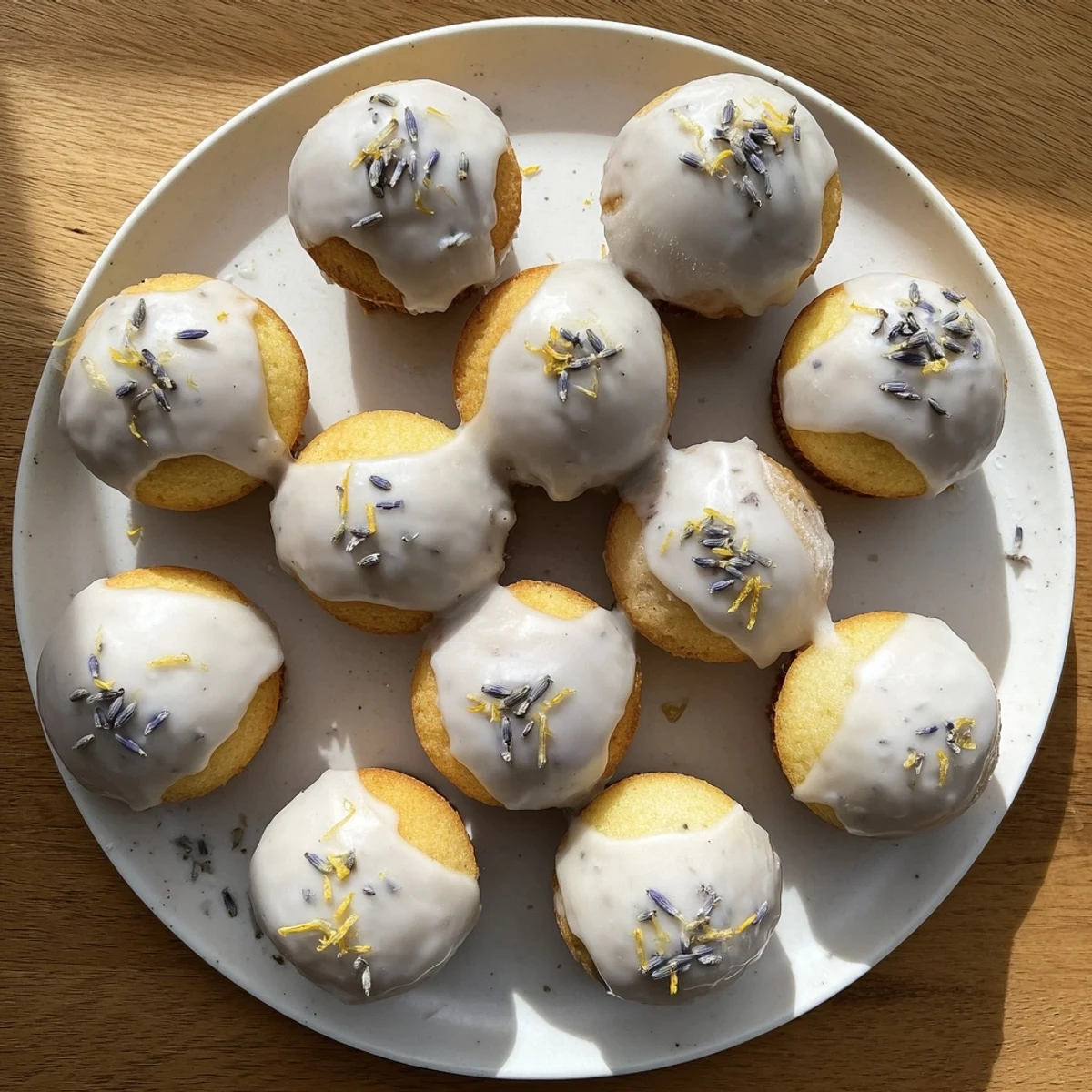 Golden mini lemon cakes drizzled with fragrant lavender glaze on a white serving plate
