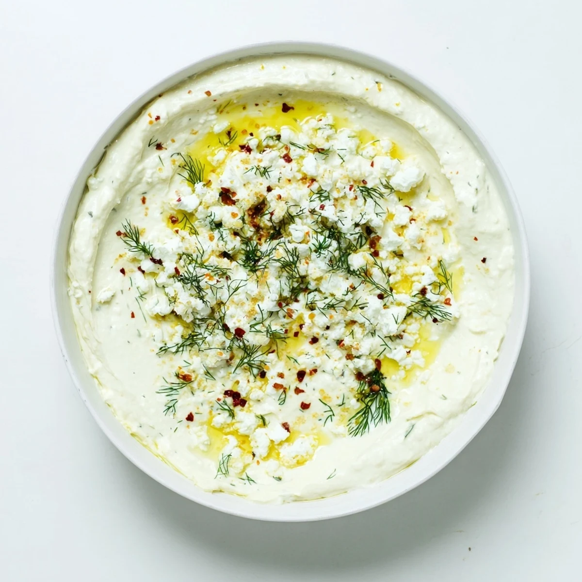 Smooth classic feta dip served in bowl with fresh pita bread and vegetable crudités