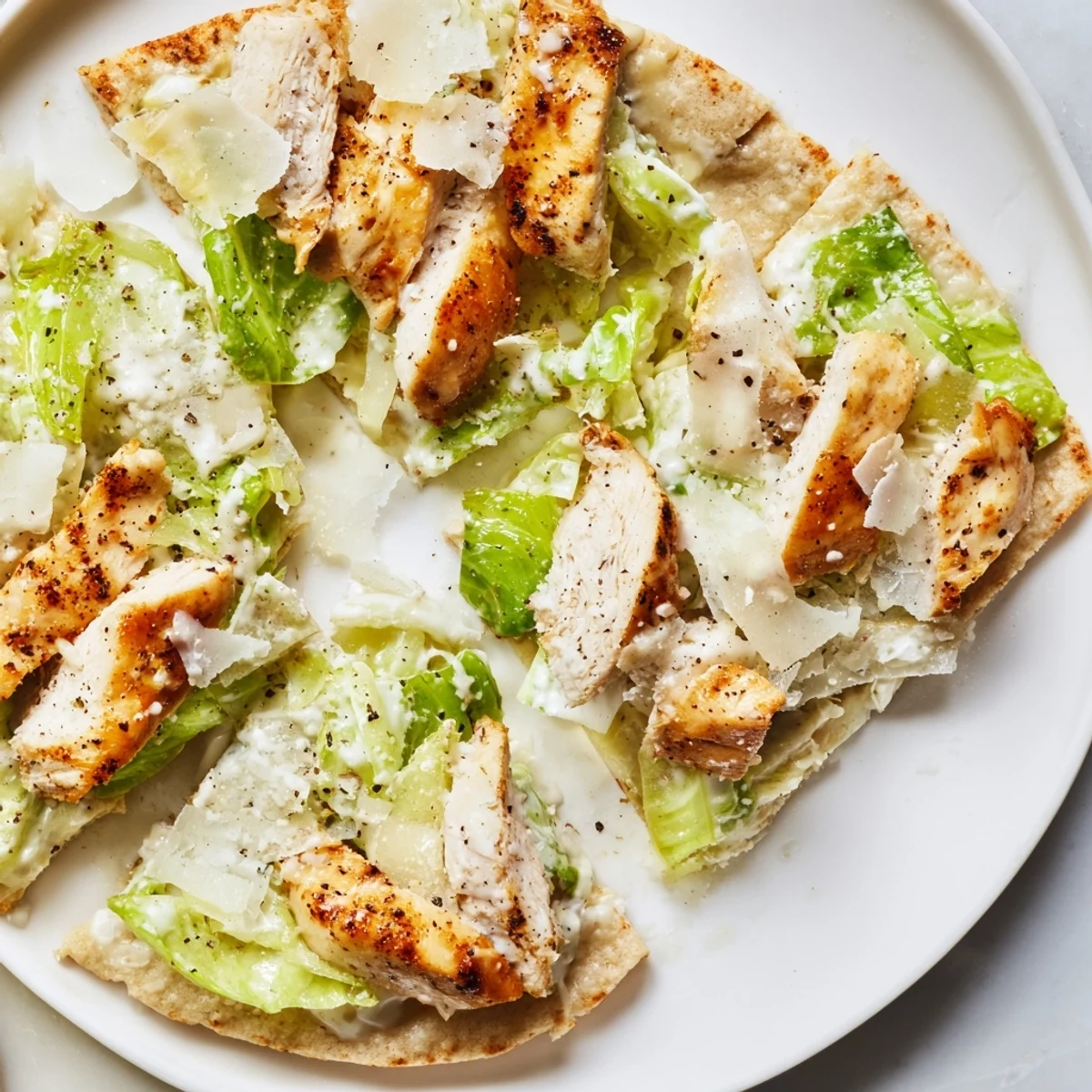 Golden chicken Caesar flatbread topped with melted cheese, crisp romaine, and creamy dressing