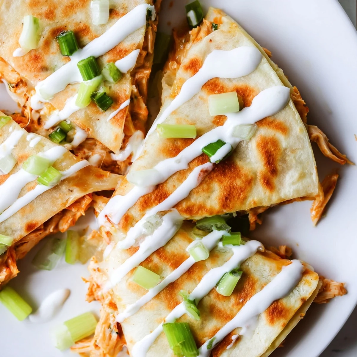 Spicy shredded buffalo chicken quesadilla oozing melted cheese and garnished with fresh green onion slices