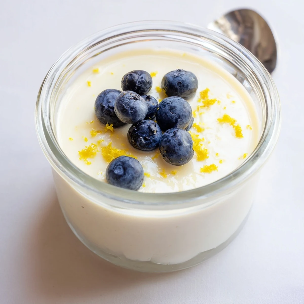 Creamy lemon posset dessert topped with bright berries and shortbread cookie