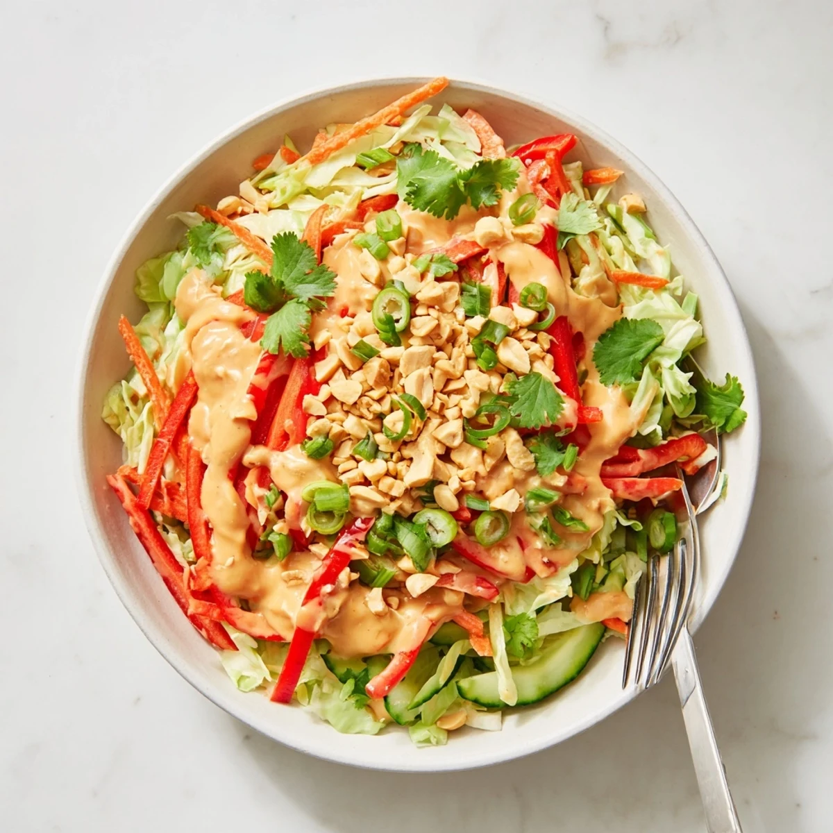 Fresh vegetable bowl topped with rich Thai salad peanut sauce and scattered crushed peanuts