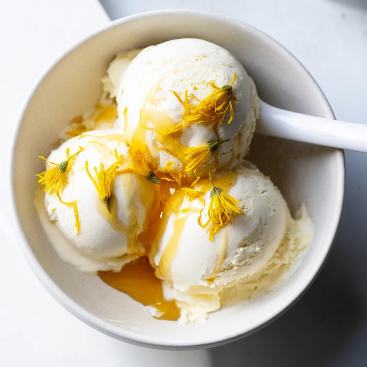 Rich floral dandelion honey ice cream topped with bright yellow dandelion petals for spring