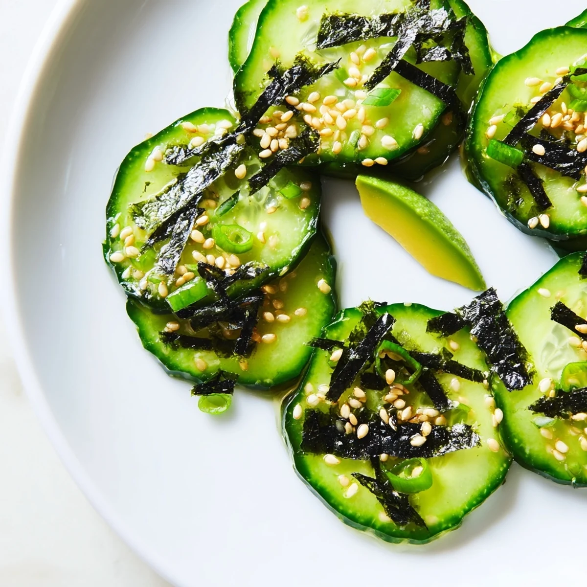 Crisp sushi cucumber salad garnished with nori strips and sesame seeds in bowl