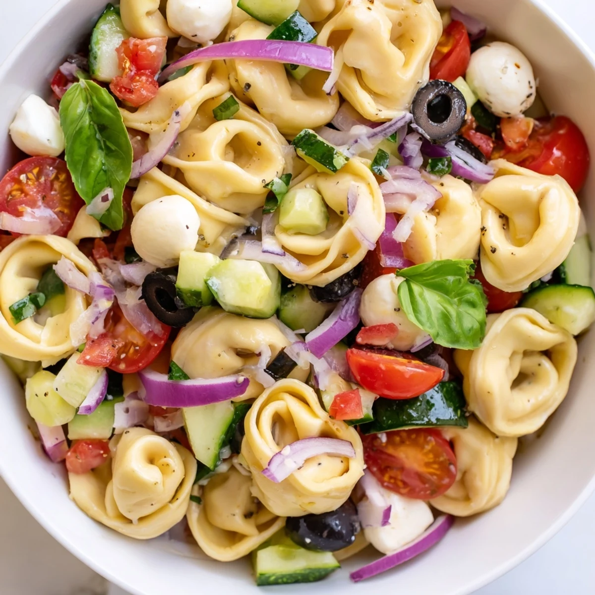 Creamy cheese tortellini salad tossed with cherry tomatoes, cucumber, and fresh mozzarella balls