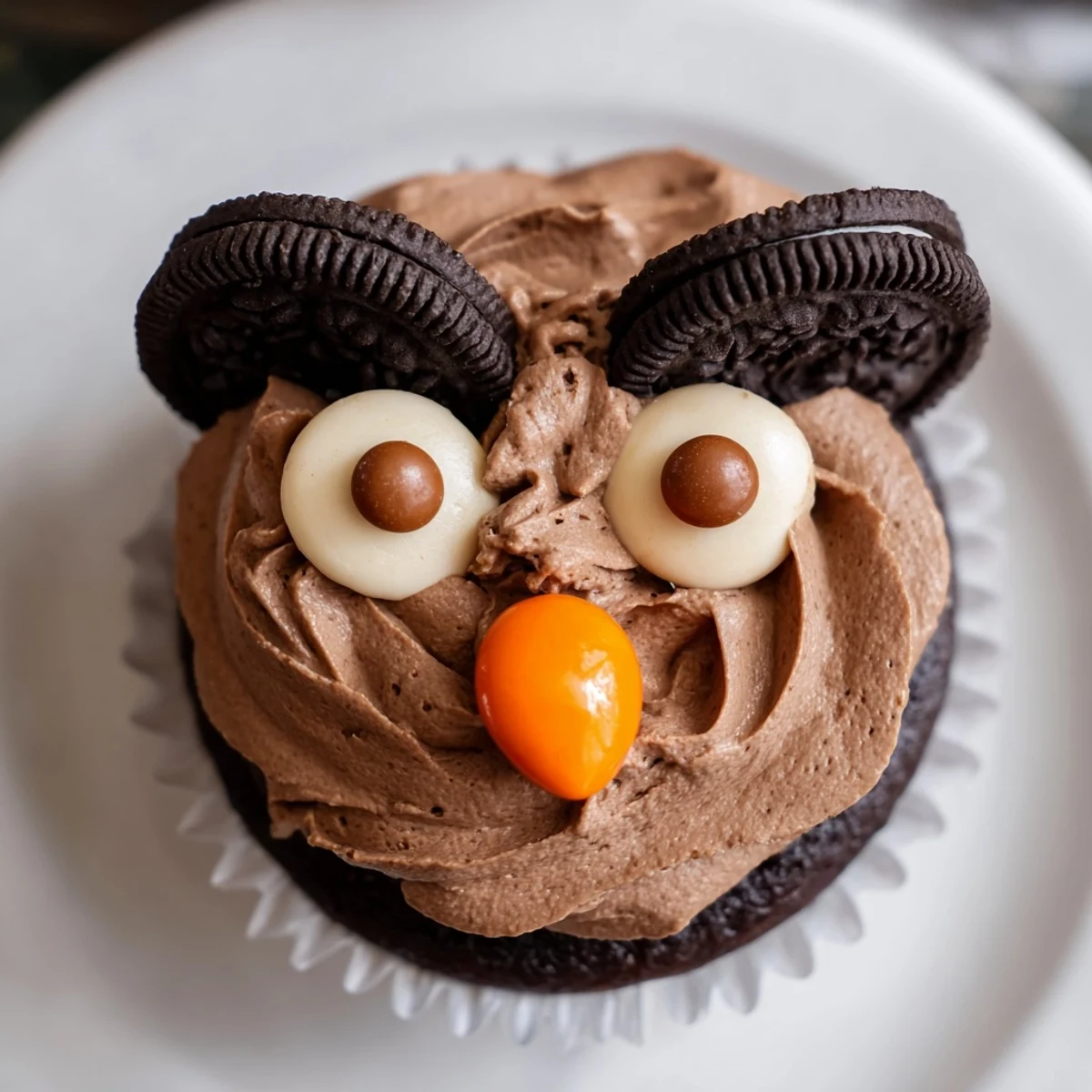 Cute Oreo Owl Cupcakes with chocolate frosting eyes and candy beaks on a rustic tray