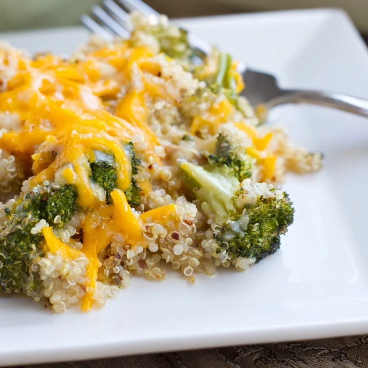 Golden creamy broccoli quinoa casserole bubbling in a baking dish with melted cheddar