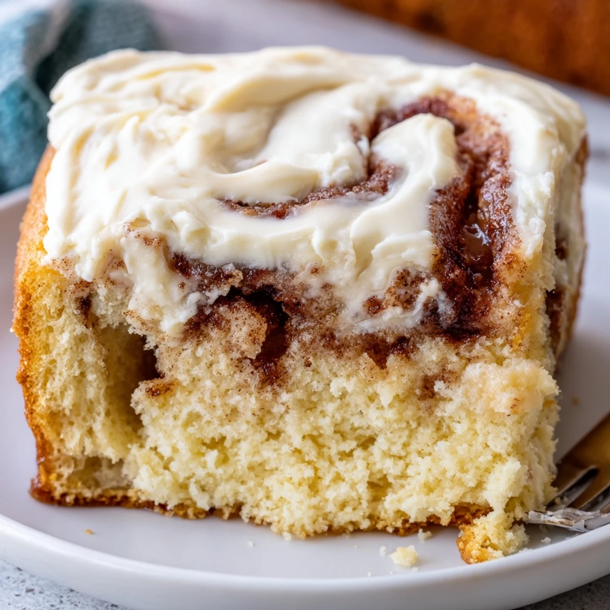Warm Cinnamon Roll Poke Cake with gooey cinnamon swirls and creamy frosting