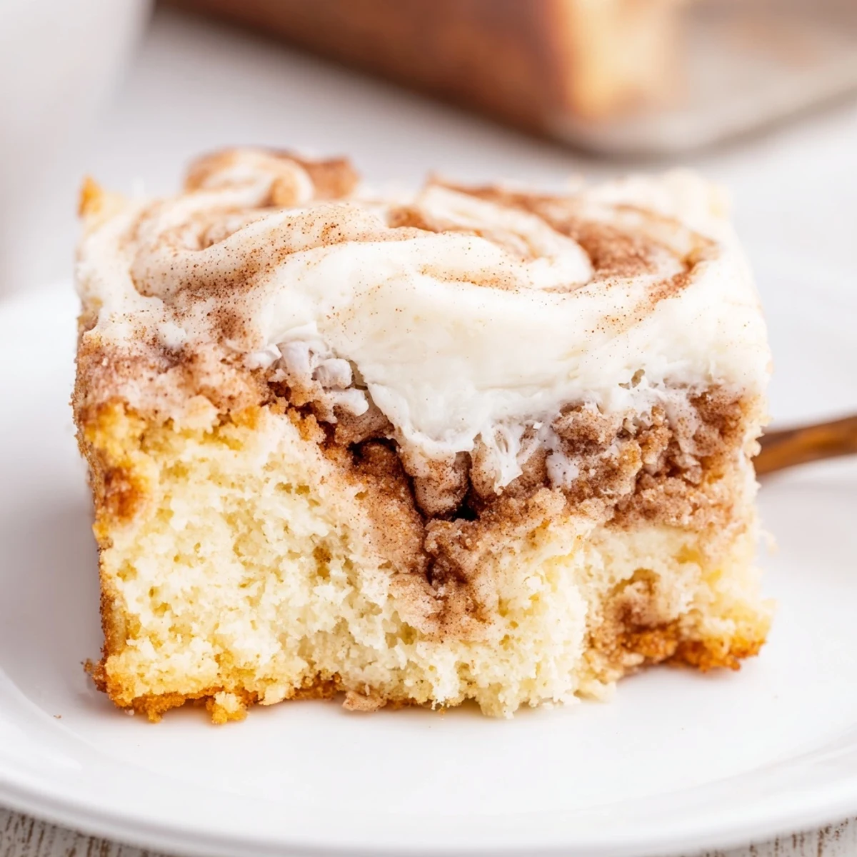 Cinnamon Roll Poke Cake sliced, served warm with vanilla ice cream