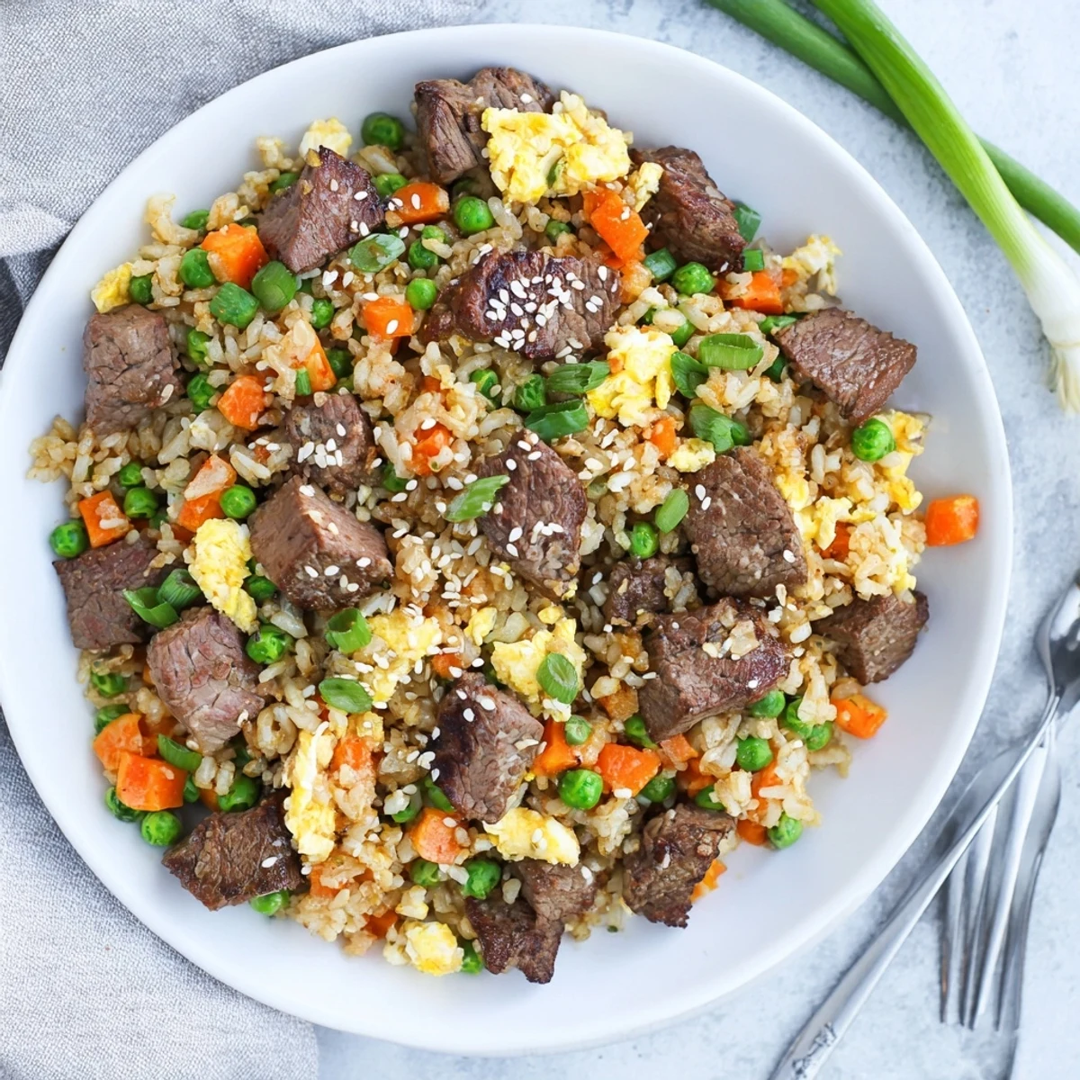 Savory hibachi steak fried rice plated with sesame seeds and fresh green onions for a crowd-pleasing dinner