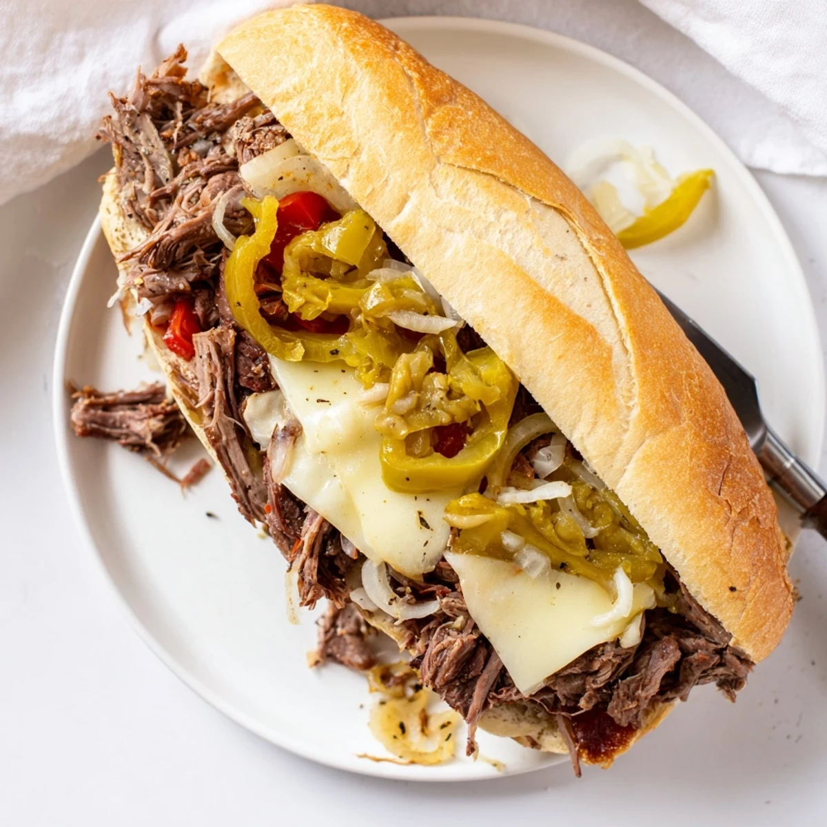Tender shredded Italian beef sandwiches topped with spicy pepperoncini on crusty hoagie rolls