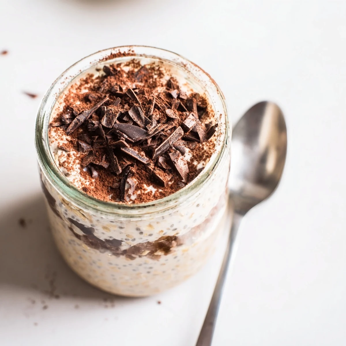 Creamy tiramisu overnight oats layered with mascarpone and dusted with cocoa in glass jars