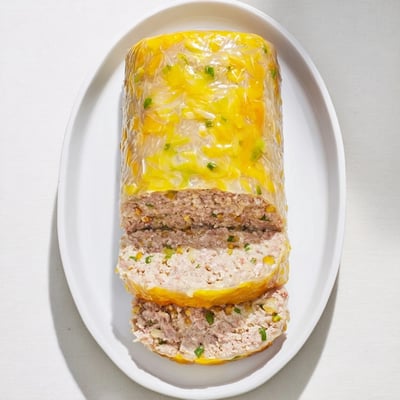 Sliced Vietnamese Cha Trung Hap steamed meatloaf served on white rice with pickled vegetables for a tangy pairing.