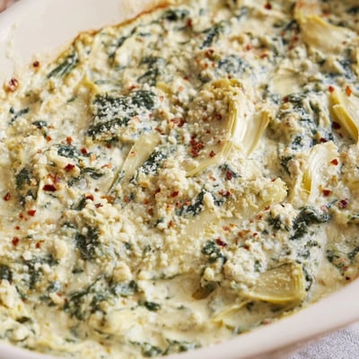 The creamy Spinach Artichoke Dip Ultimate Recipe is garnished with fresh parsley and crusty bread slices.